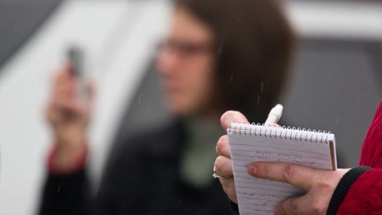 A blurred photo of a journalist and a notepad 
