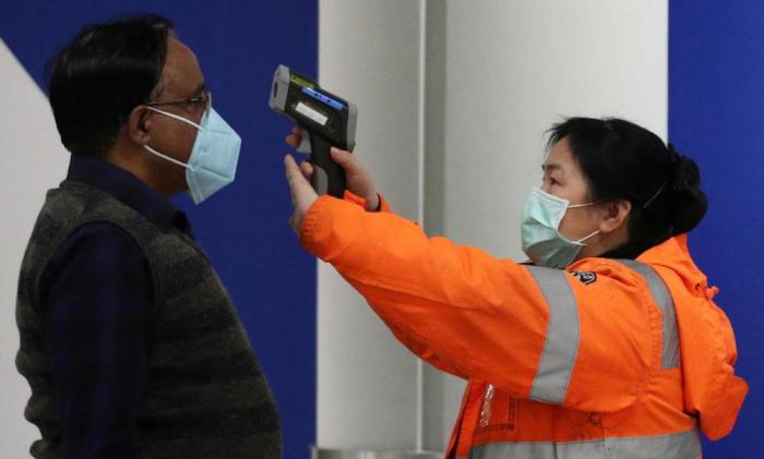 A passenger arriving in Hong Kong gets his temperature checked by a worker using an infrared thermometer