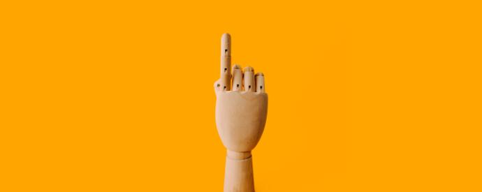 A wooden mannequin hand pointing up