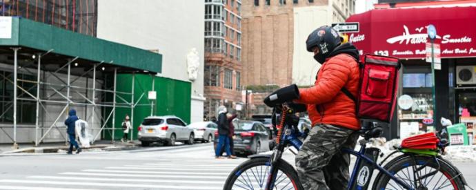 Person on a bike with delivery backpack on a busy city street