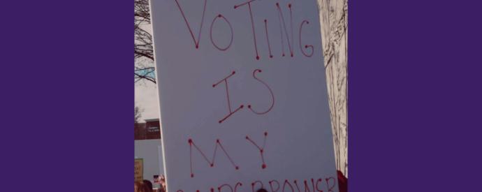 Protest placard with text: "VOTING IS MY SUPERPOWER" on purple background