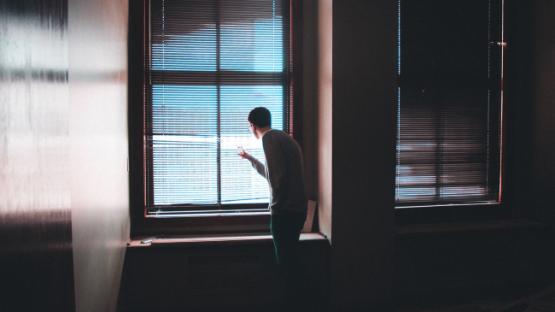 Man looking at the window behind curtains