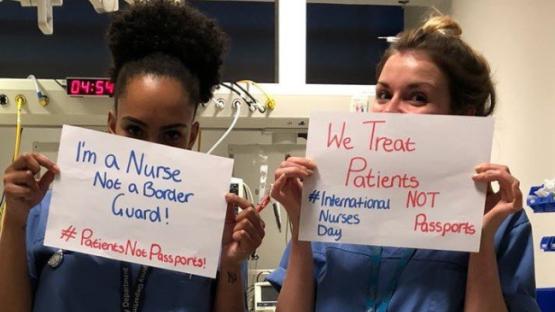 Nurses holding signs that say "We treat patients, not passports"