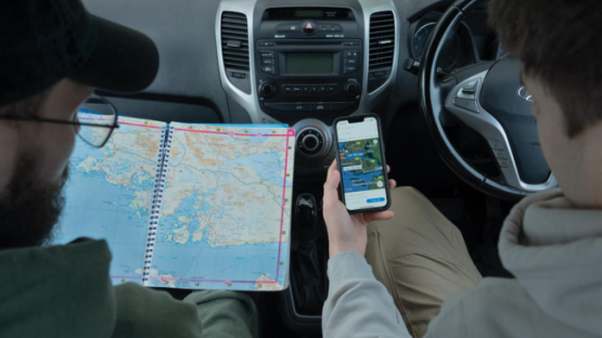 Two people looking at a map and Google Maps in a car