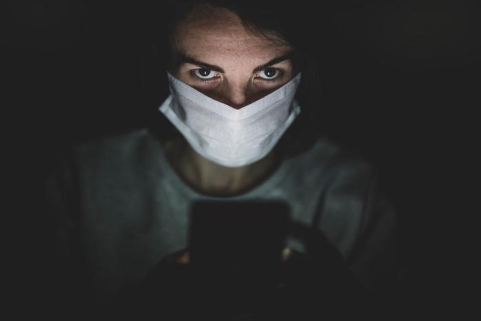 person wearing face mask looking at phone