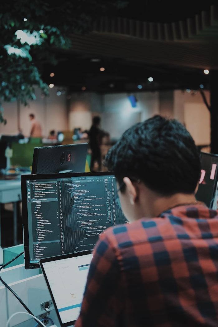 Man back to camera facing a screen with code in an open space