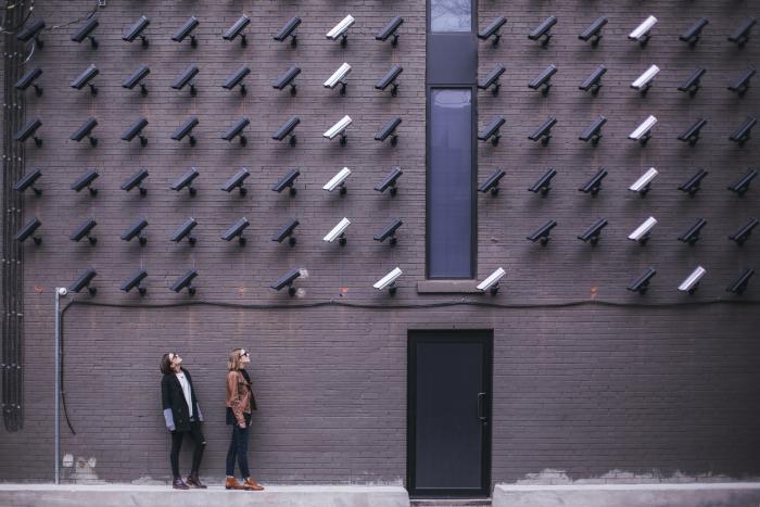 two women looking at surveillance camera art installation