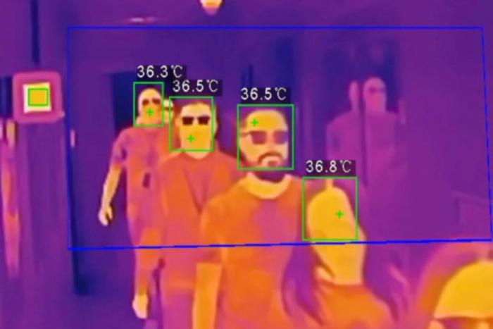 multicoloured image showing a thermographic image of several people, each with a decreasing measured temperature as they're further from the camera