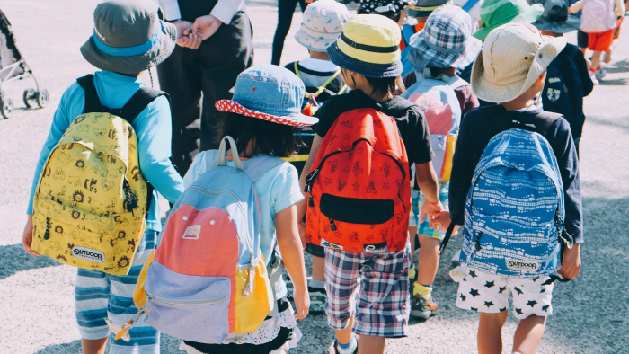 A group of small children hold hands on the walk to school, Photo by note thanun on Unsplash