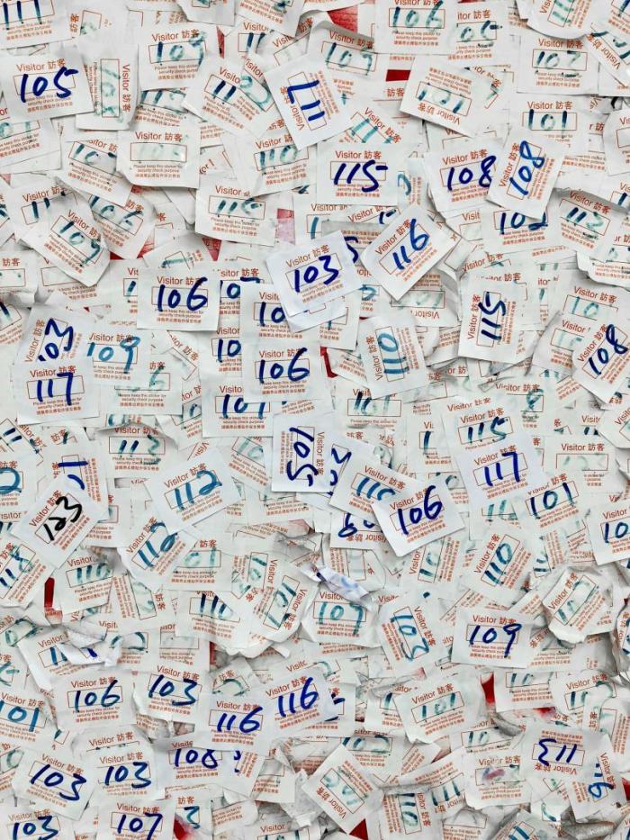 A pile of visitor number badges with different numbers on