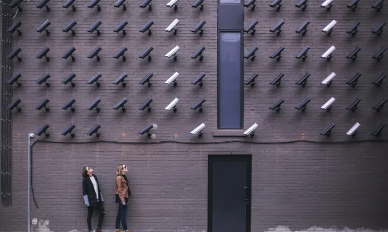 two women looking at surveillance camera art installation