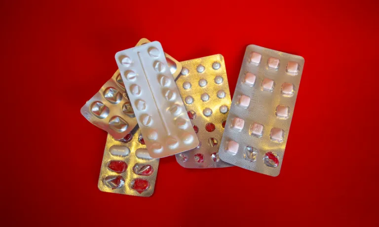Generic silver blister pill packets on a red background