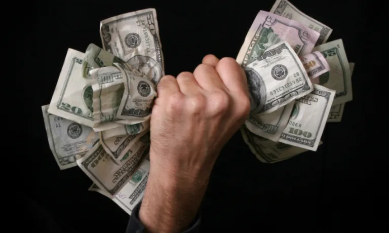 A wad of money being grabbed in a hand