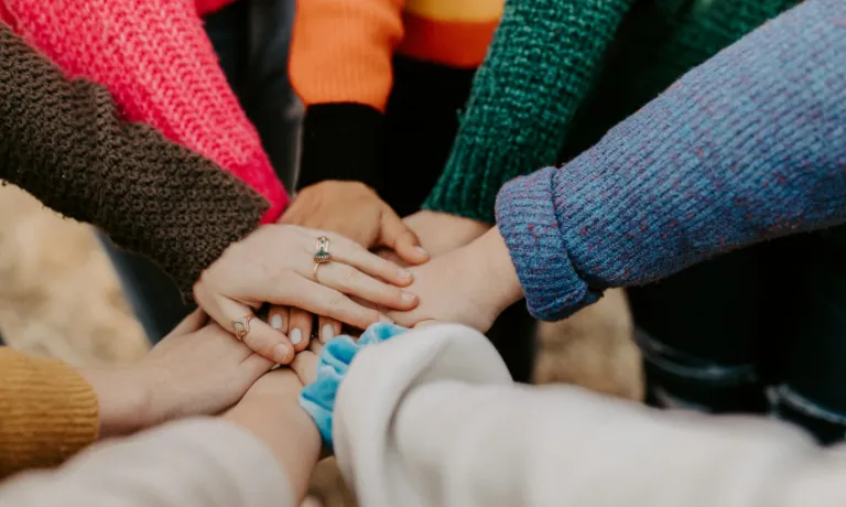People in colourful sweaters holding hands