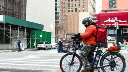 Person on a bike with delivery backpack on a busy city street