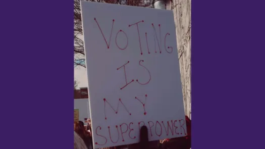 Protest placard with text: "VOTING IS MY SUPERPOWER" on purple background