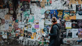 woman looking at hundreds of ads on a wall