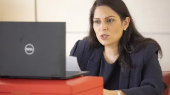 Picture of Priti Patel sitting at her computer